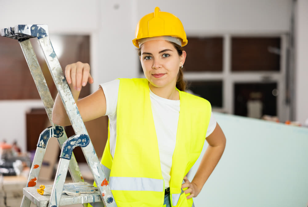 Portrait of woman builder in protective helmet and vest