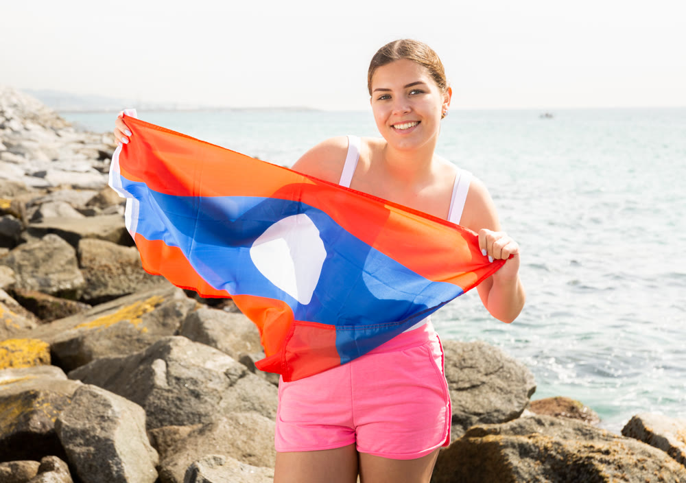Happy girl waving the flag Laos on the lake on sunny day