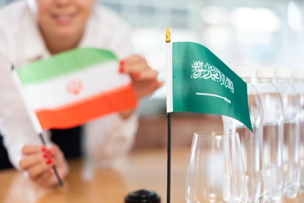 Unrecognizable girl sets midget flags of Saudi Arabia and Iran before international negotiations