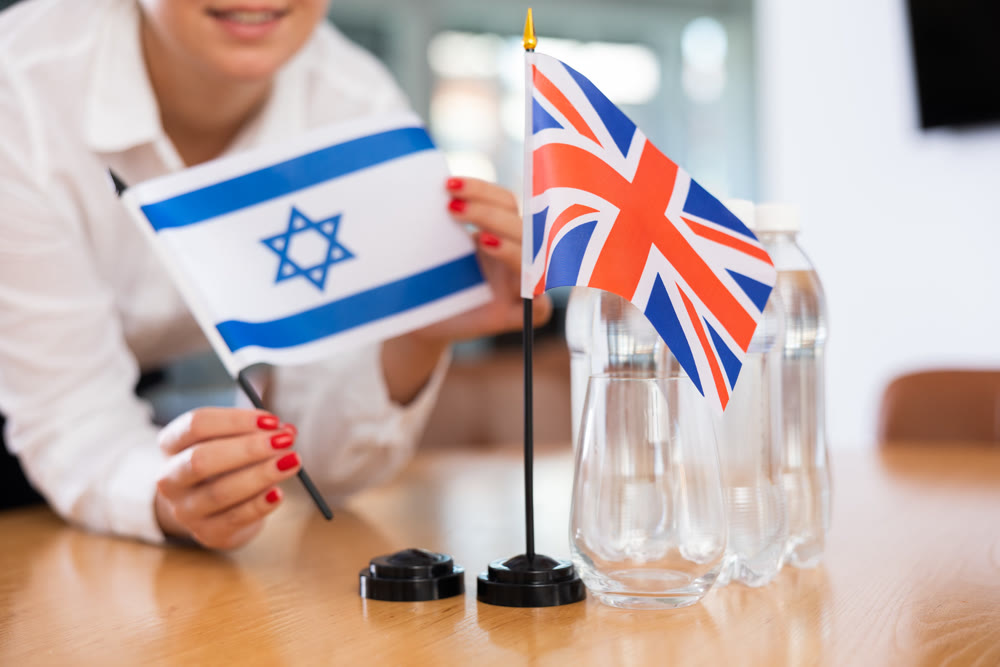 Office coordinator setting flags of Israel and United Kingdom on table