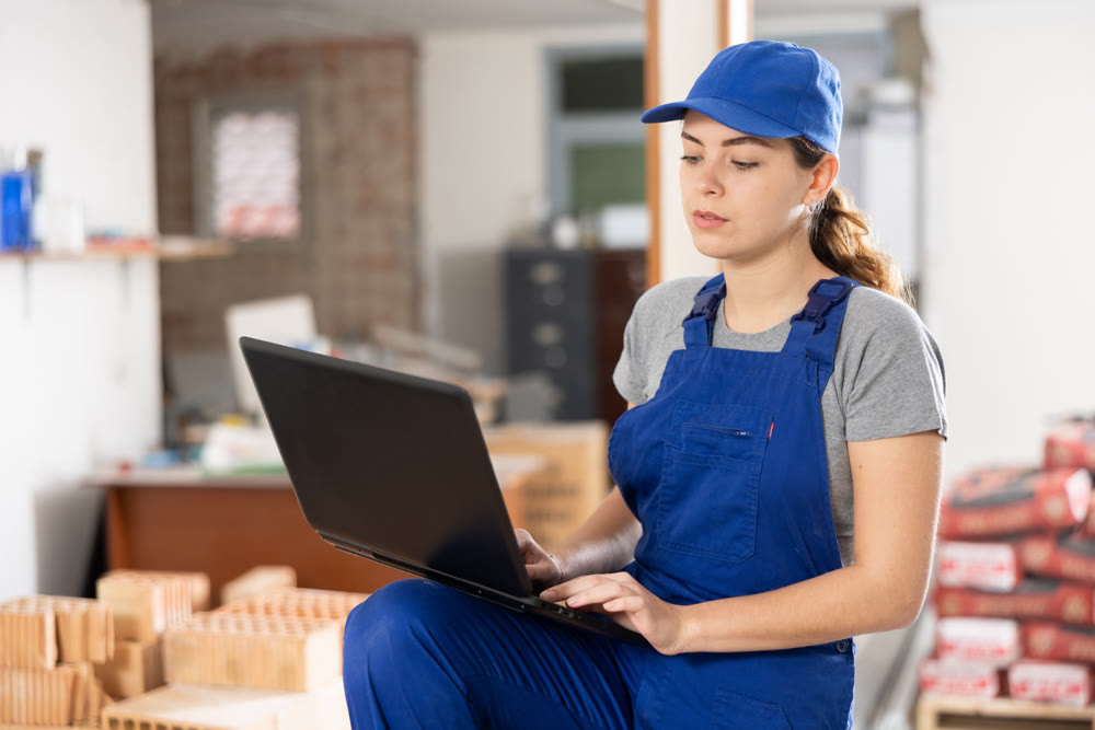Young female contractor using laptop at construction site indoors
