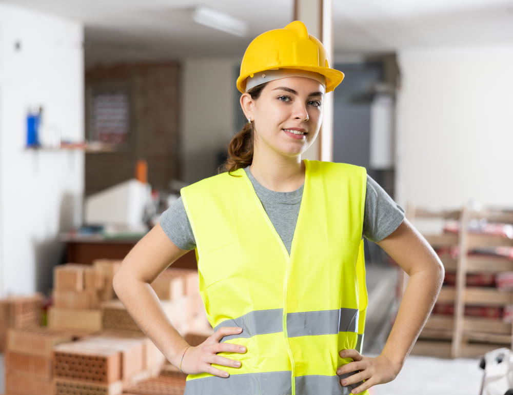 Young woman construction worker standing inside apartment