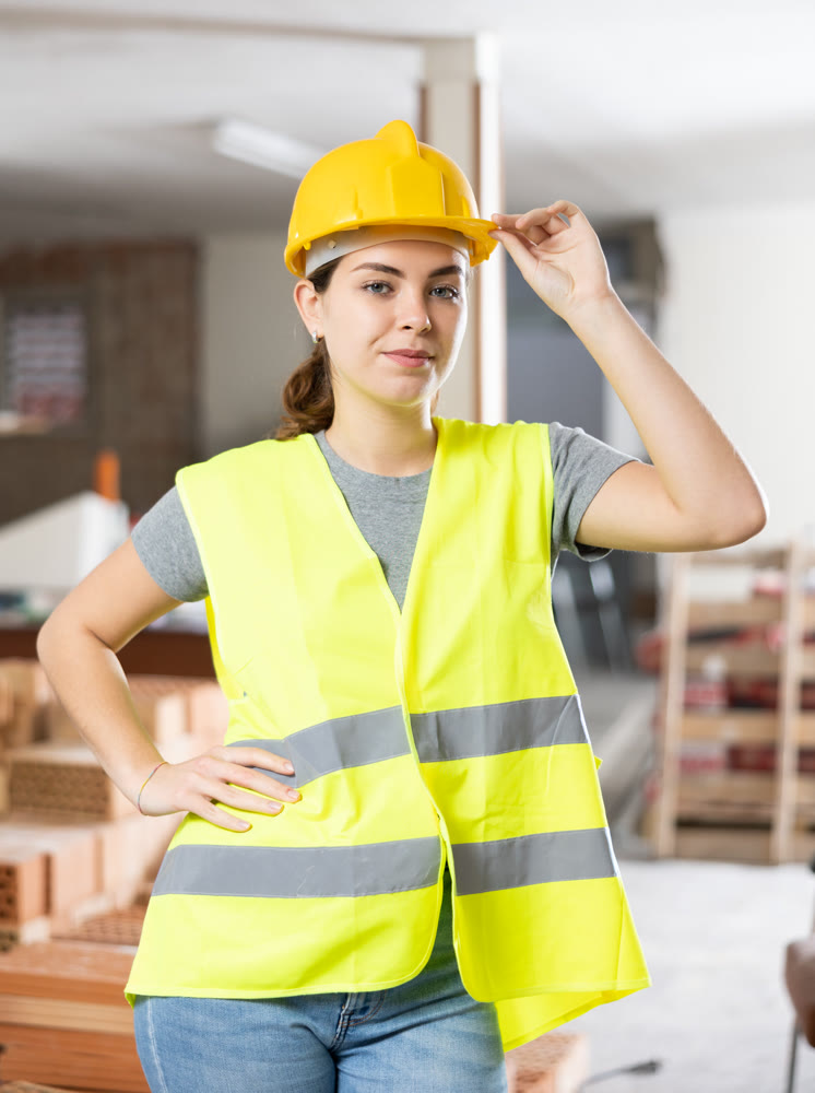 Portrait of positive woman builder standing in construction site