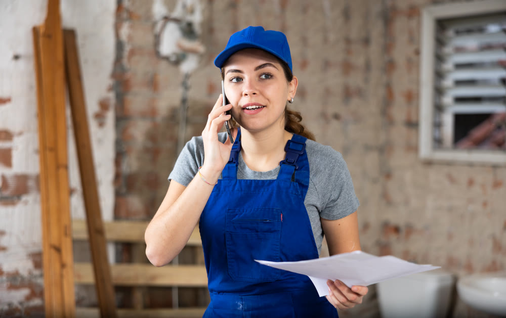 Female foreman holding papers and talking on phone at construction site