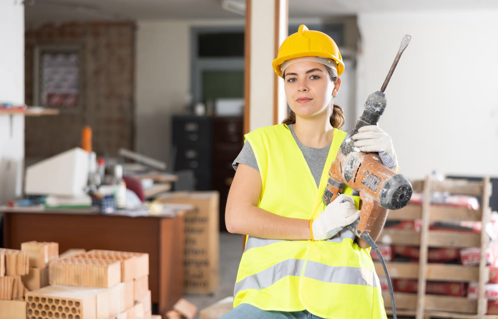 Portrait of positive woman builder standing in construction site