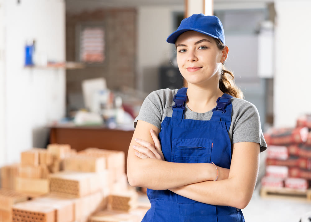Portrait of positive woman builder standing in construction site