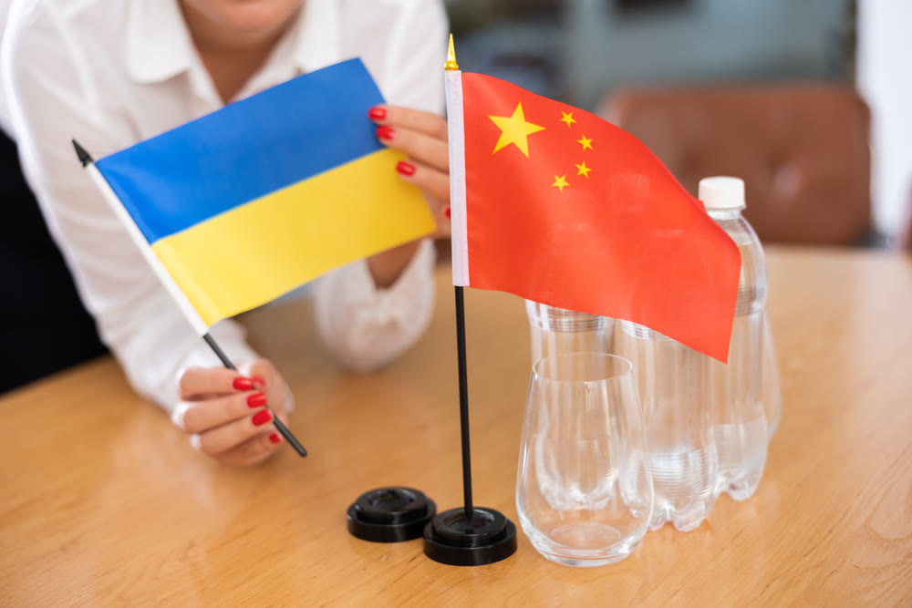 Unrecognizable girl sets midget flags of China and Ukraine before international negotiations
