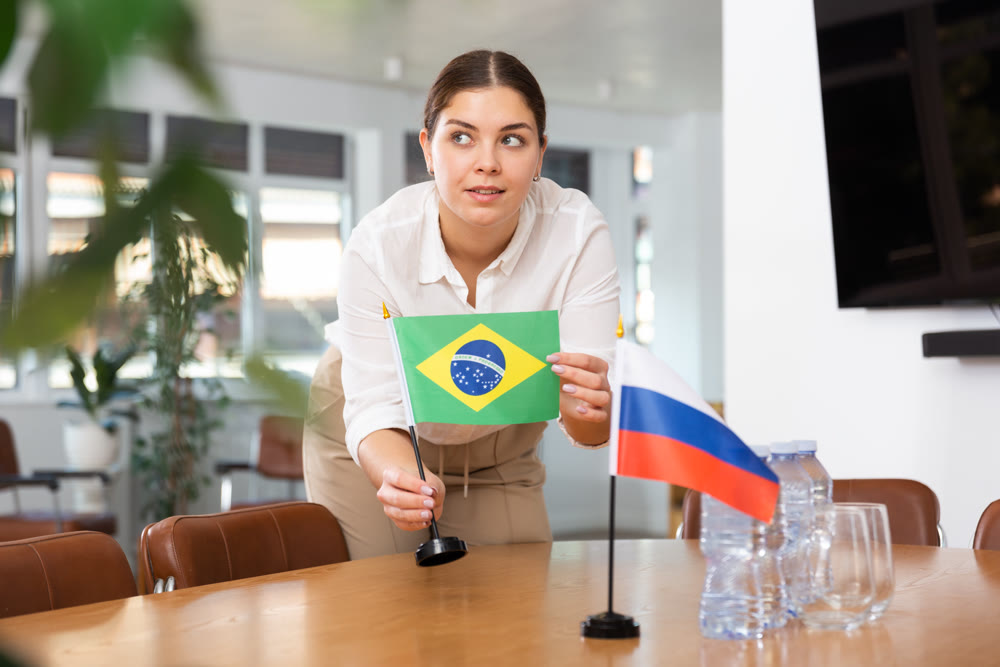 Young woman puts flags of Brazil and Russia on table