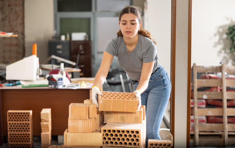 Young woman stacking bricks at construction site