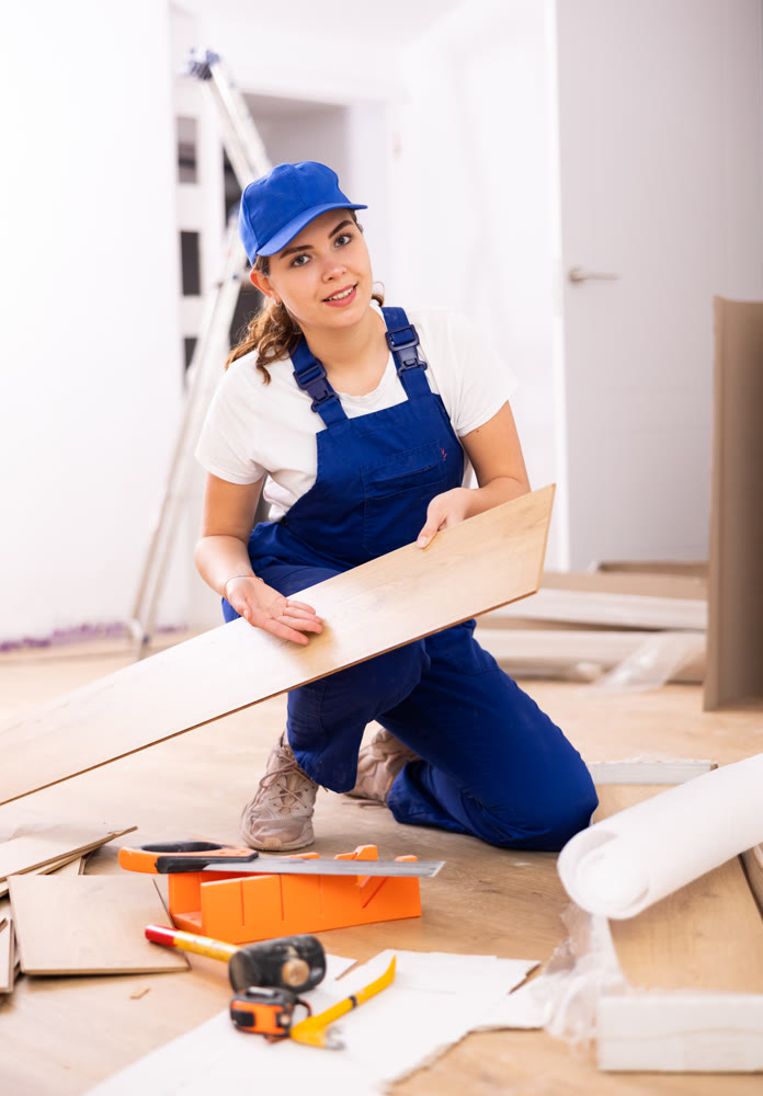 Woman builder preparing laminated boards for laying floors