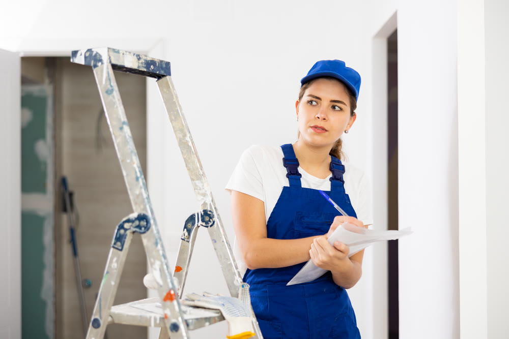 Young woman builder checking documentation in construction site