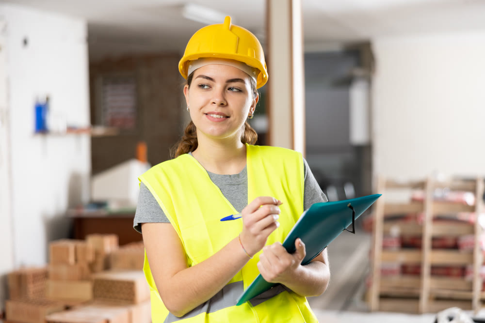 Smiling female civil engineer standing with papers at construction site