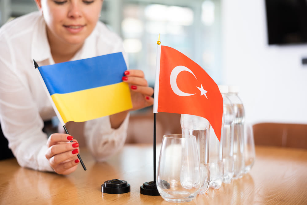 Little flag of Turkey on table and flag of Ukraine put next to it by young woman