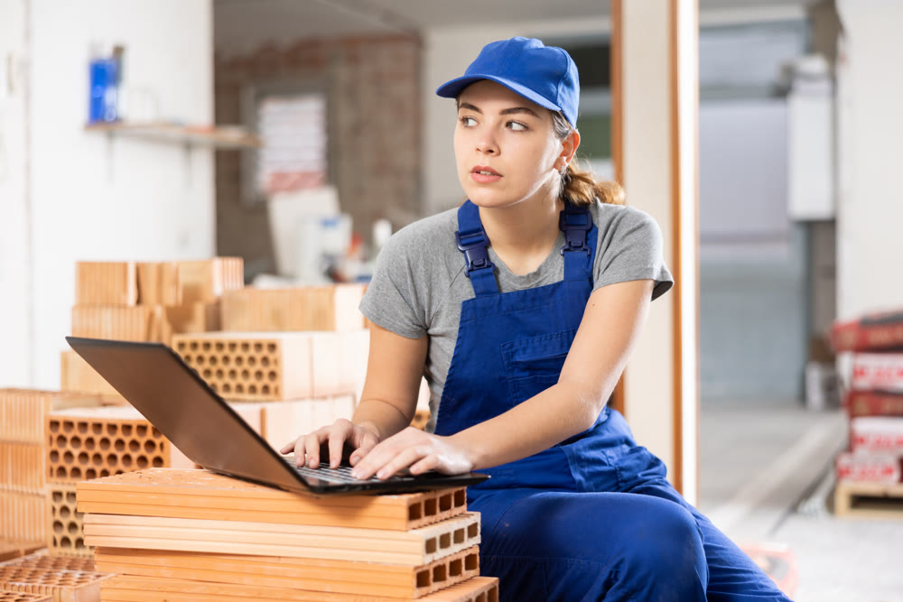 Female foreman working with laptop in building under construction
