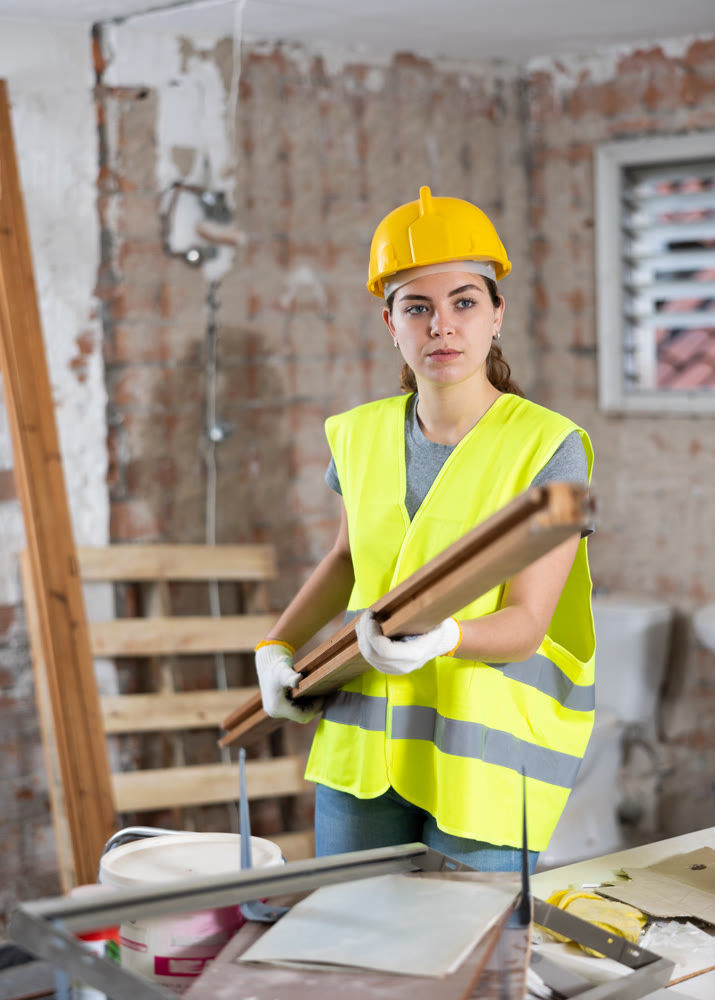 Female carrying wooden panel on construction site