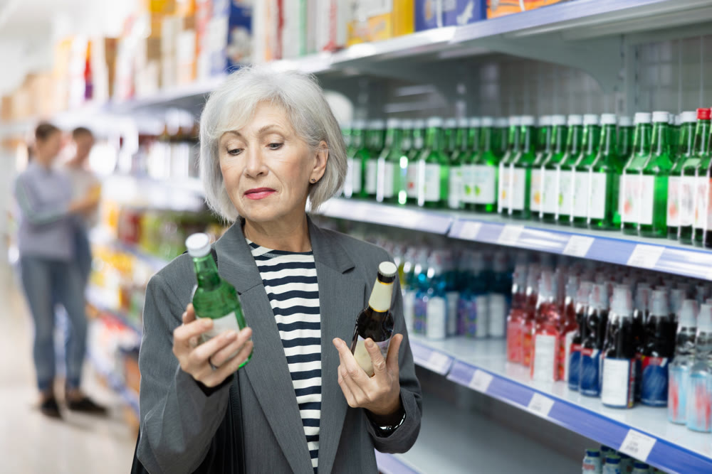 Senior woman customer is thinking about buying spicy and unusual Korean soy wine chum churum.