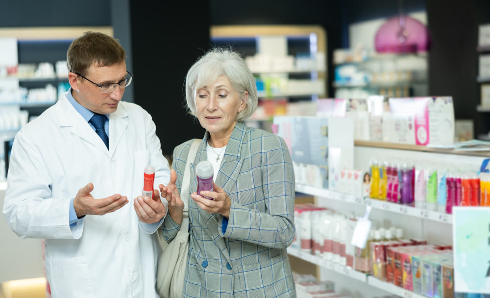 Male pharmacist gives advice to mature woman on what product intimate hygiene to buy for personal hygiene