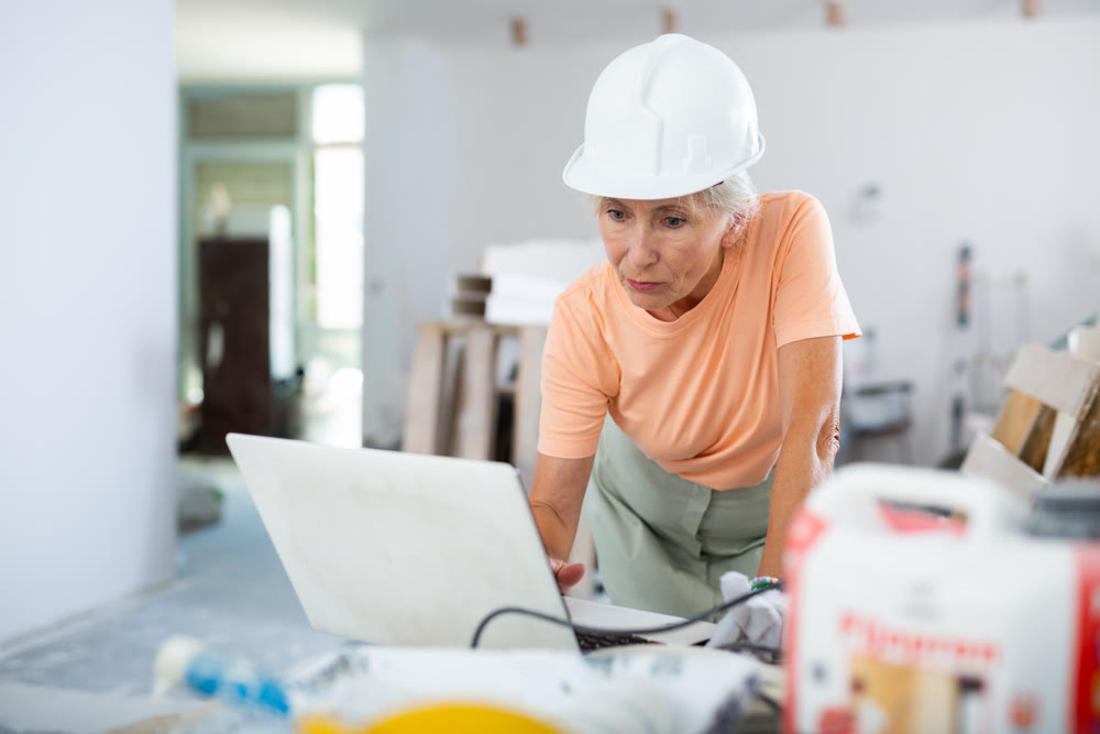 Woman using laptop in apartment under reconstruction