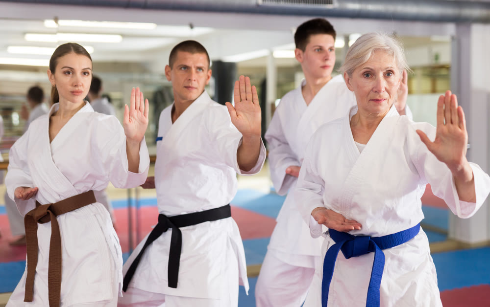 Elderly woman practicing punches during group martial arts workout