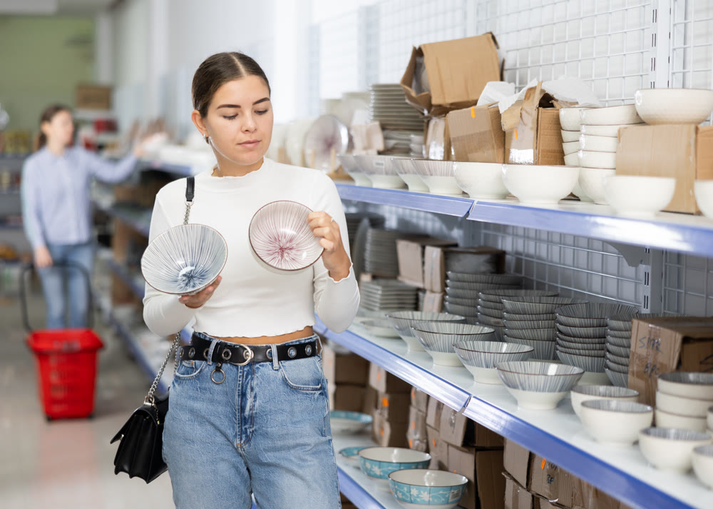 Young woman in supermarket is choosing plates with Asian pattern