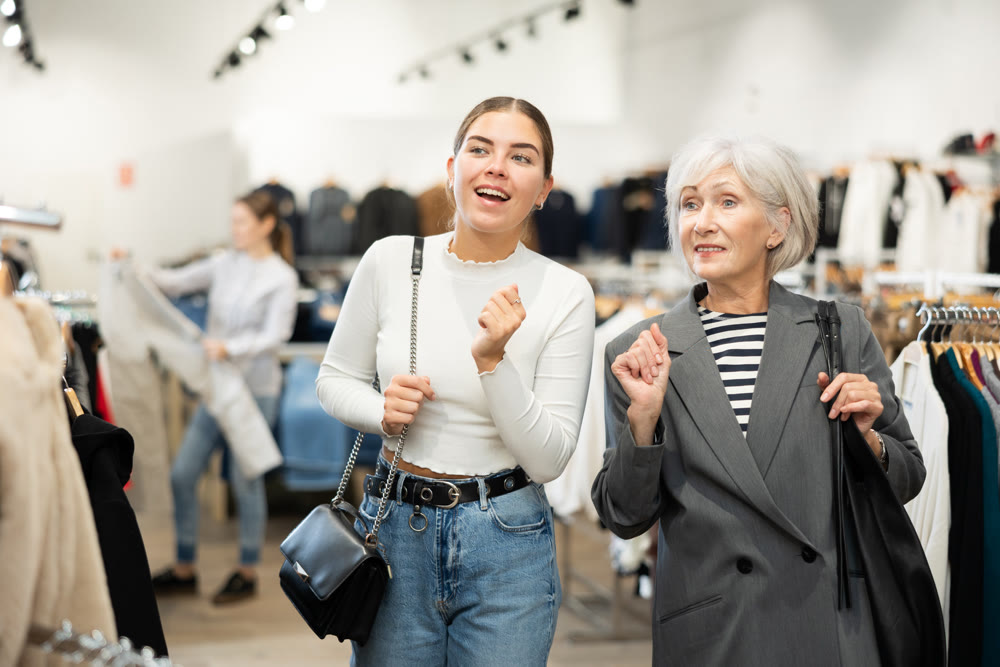 Two women customers watching large stock of clothes in clothing store
