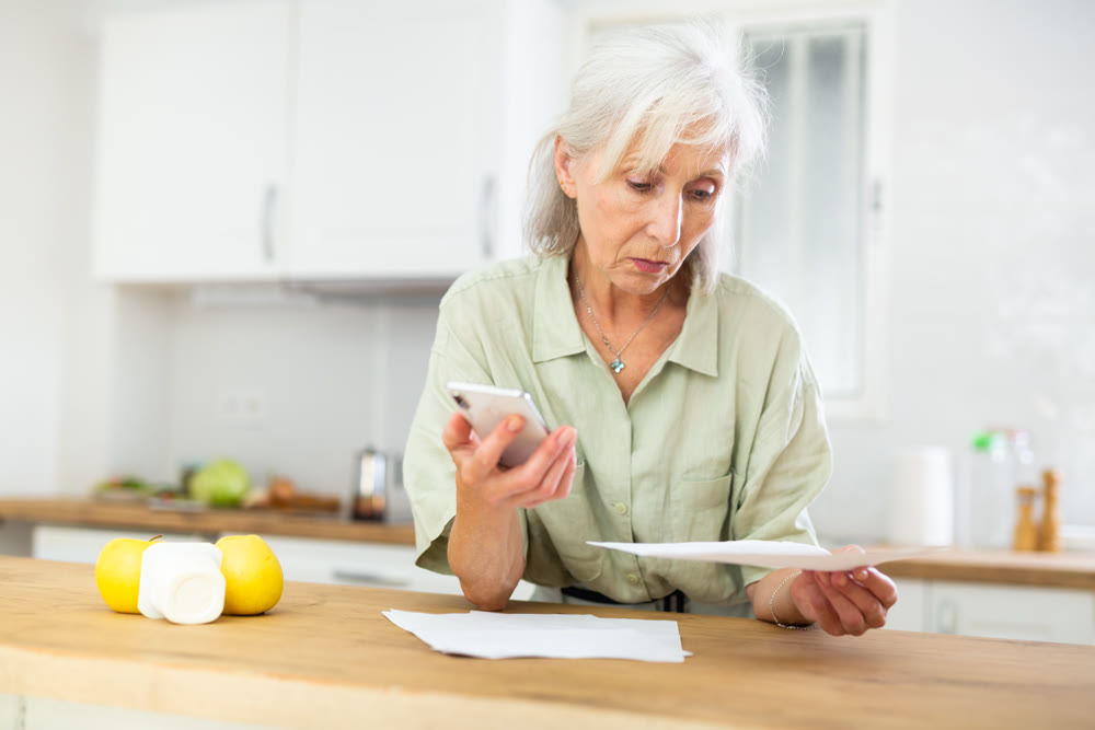 Woman using phone and working with papers
