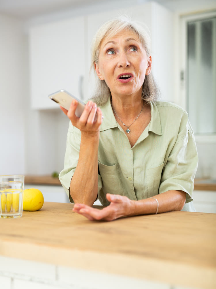 Positive senior woman using phone at home