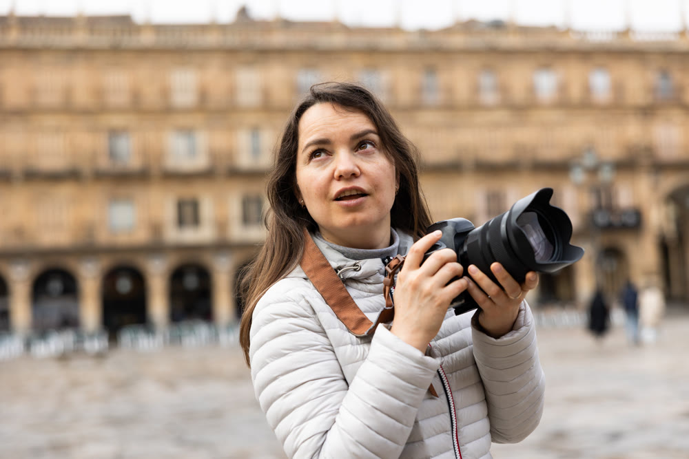Woman standing on Placa Mayor in Salamanca and using her camera