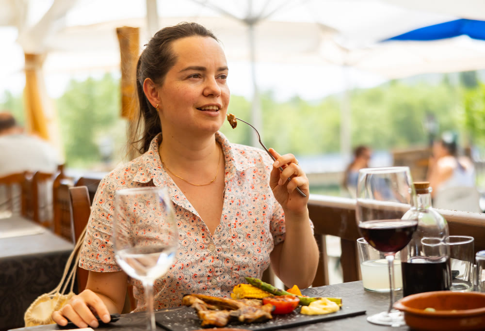 Woman eating hot dish of lamb in restaurant on an outdoor terrace