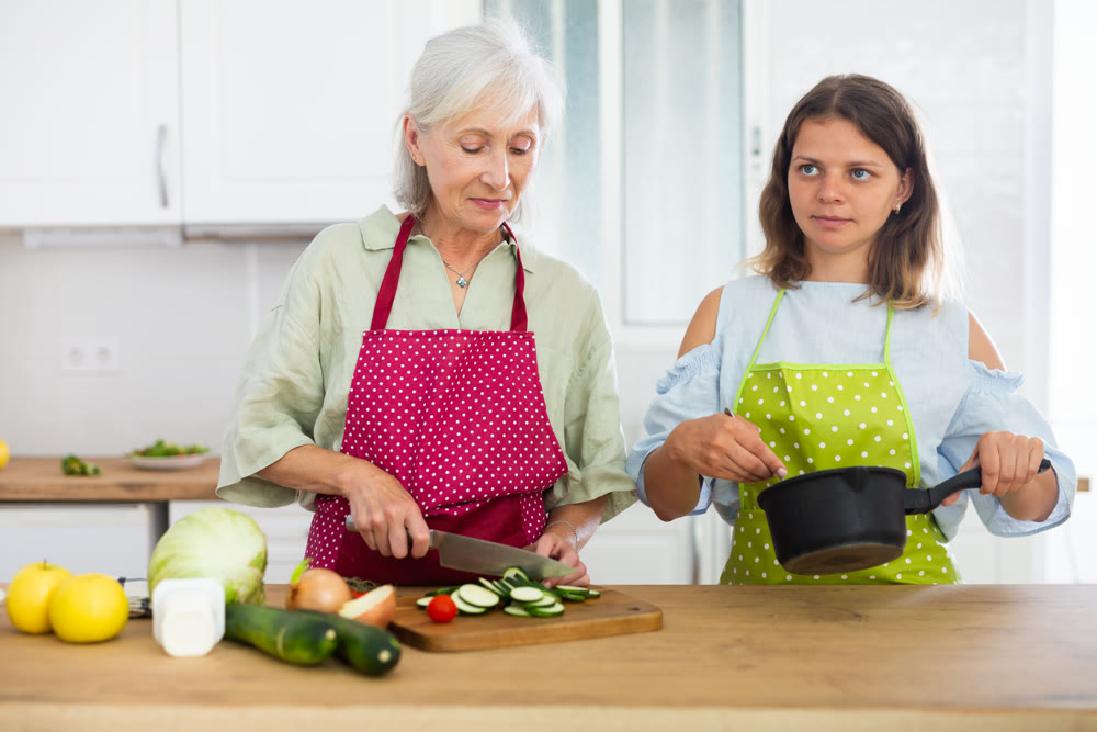Senior woman and her adult daughter cooking dinner together
