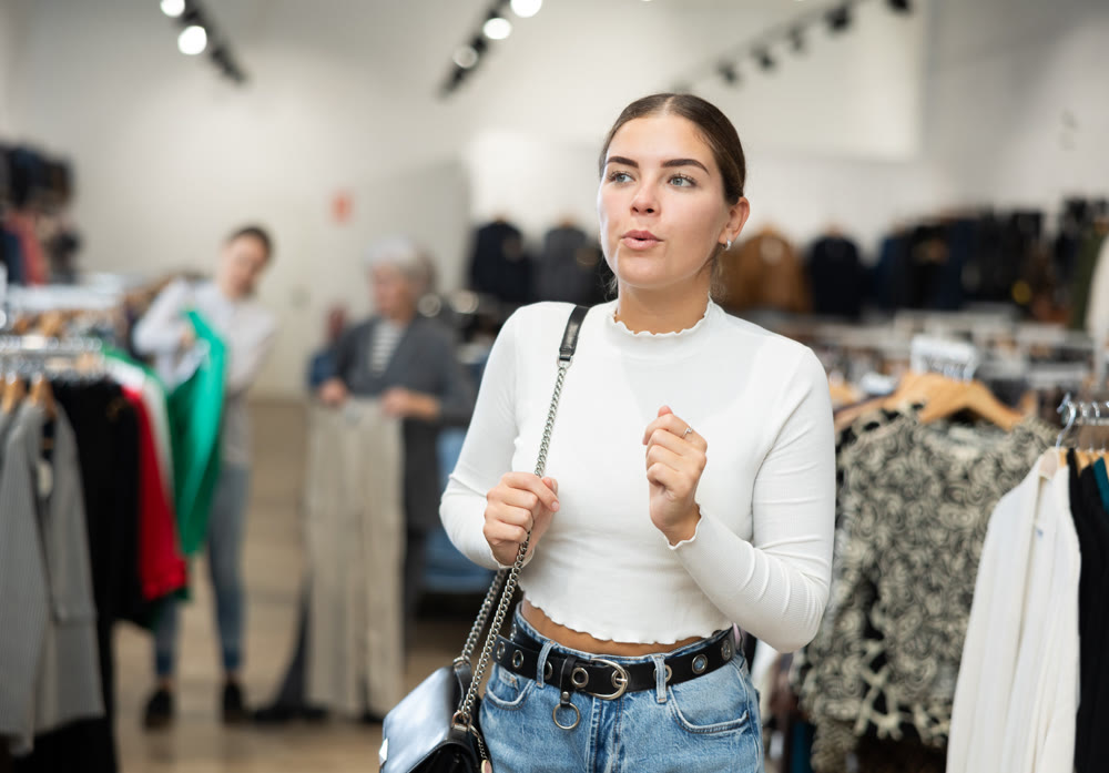 Young girl watching excitedly large stock of clothes in clothing store