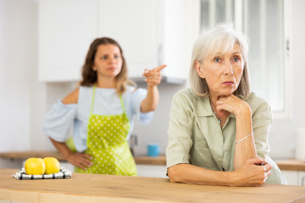 Quarrel of an elderly mother and adult daughter in the kitchen. Adult daughter is unhappy with elderly mother