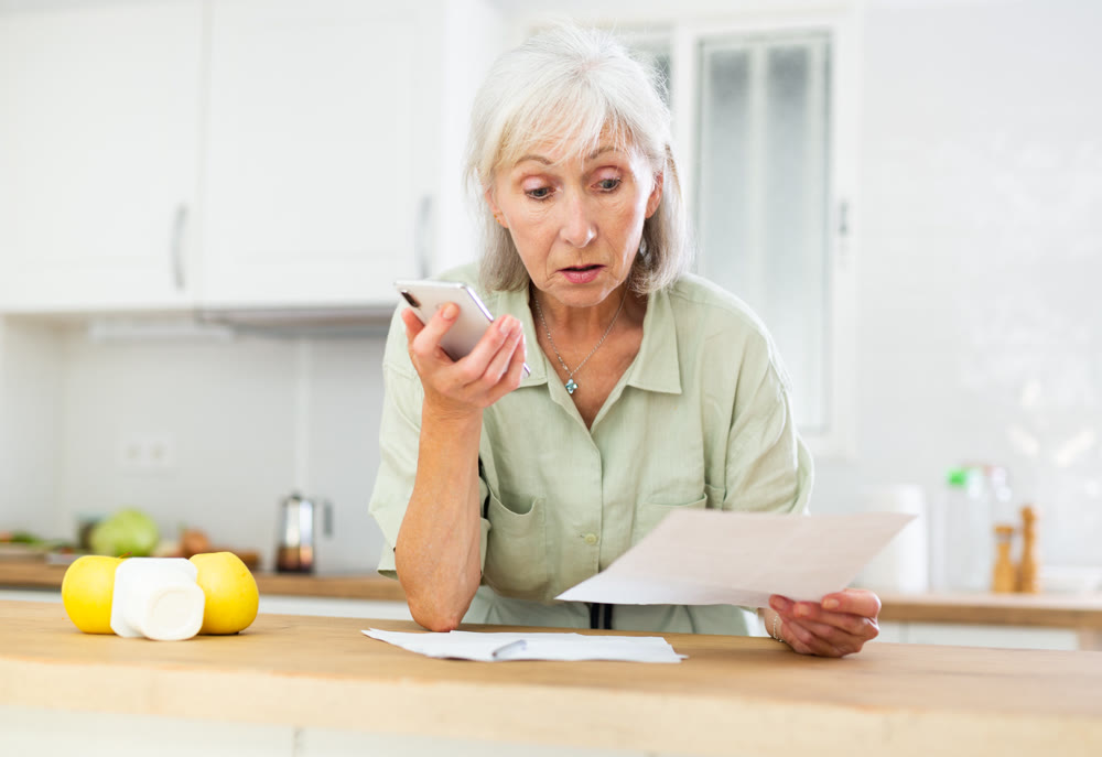 Woman using phone and working with papers