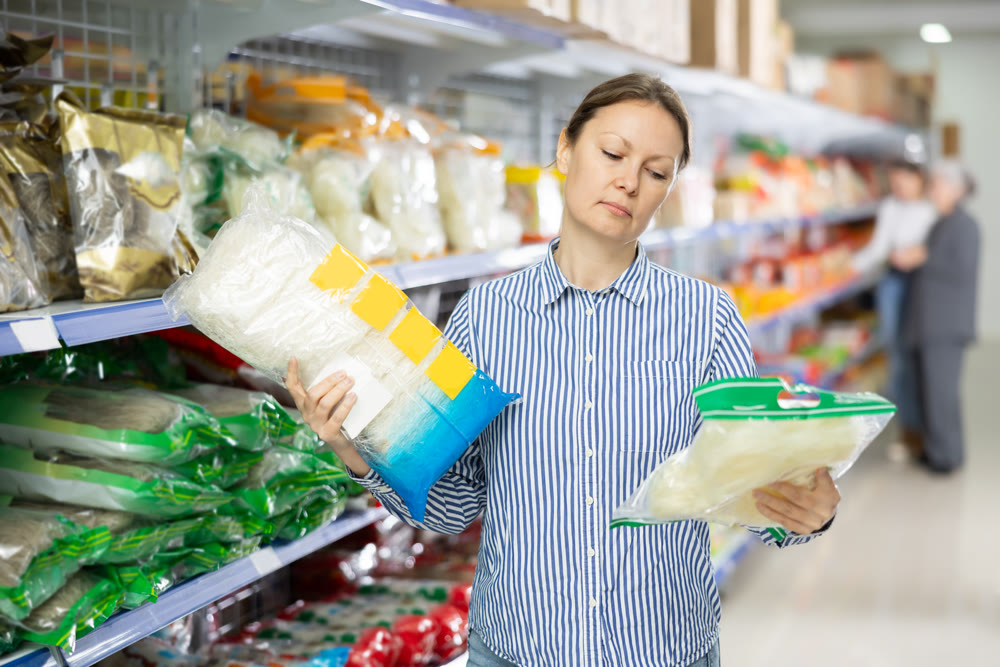 Interested female shopper choosing noodles at Asian grocery store