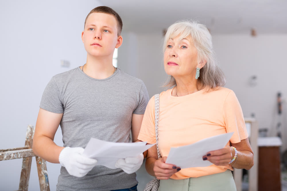 Mature woman is studying documentation with a worker, discussing something