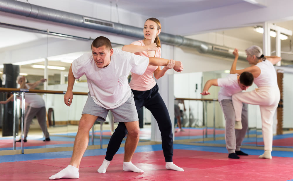 Self-defense course - a woman trains to do painful grip and painful blows to man
