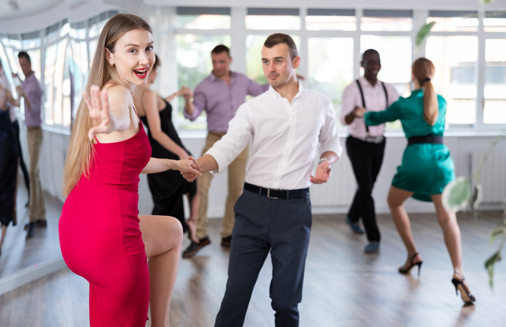 Woman and man dancing foxtrot in pair during group dance party