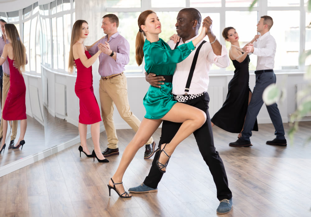 Dance training in group - men and women of different nationalities and different ages dance tango or bachata in dance studio