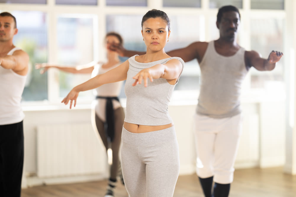 Concentrated women and men rehearsing ballet dance in class