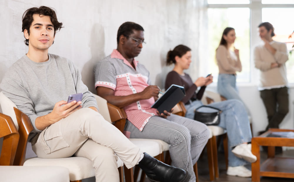 Young guy sitting in a queue at a modern office