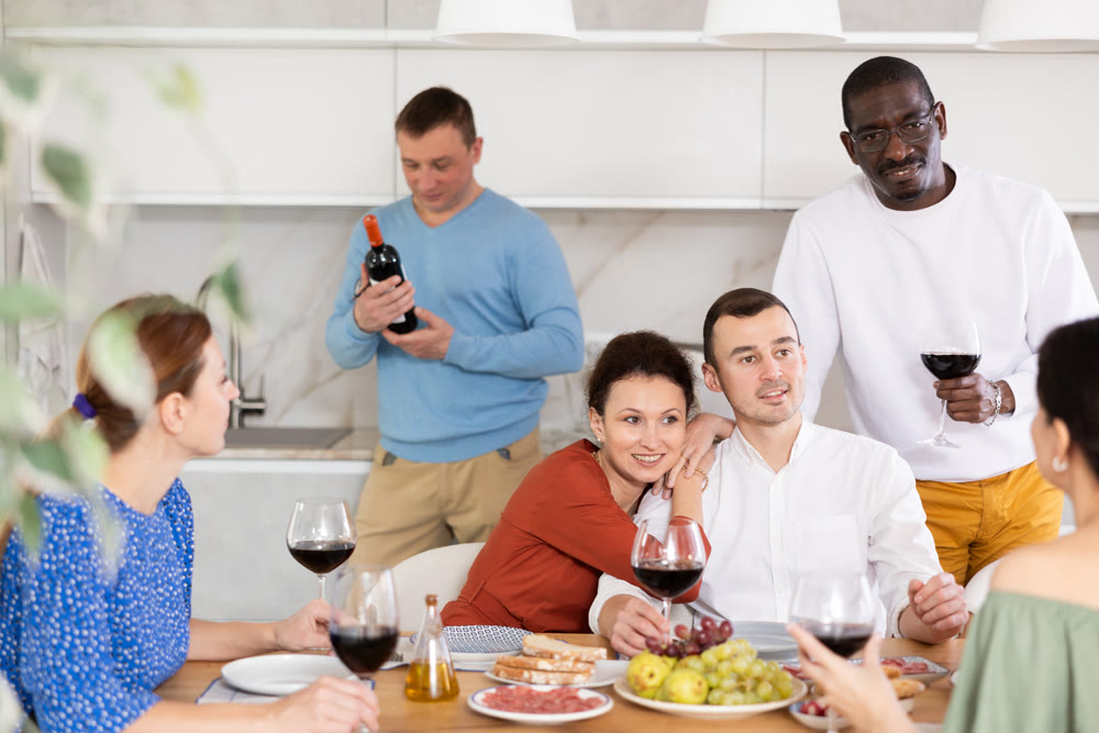 Cheerful women and men enjoying friendly company during house party