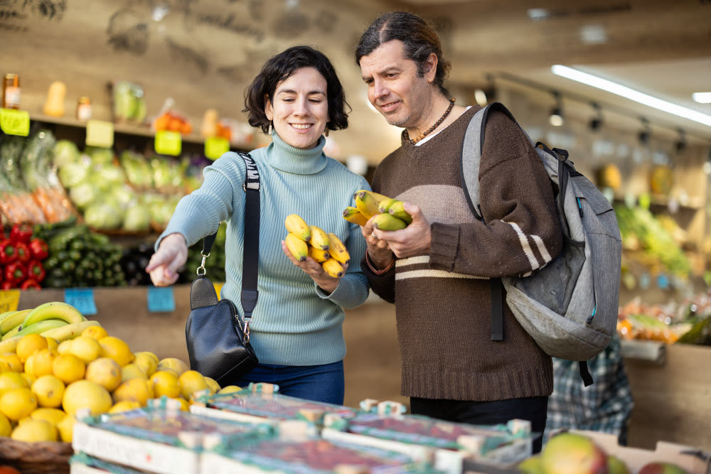 European couple standing near banana counter