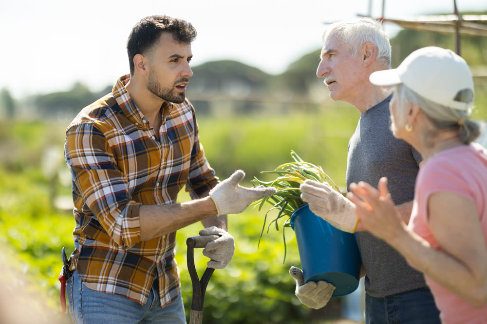 Elderly couple and young man arguing on farm field