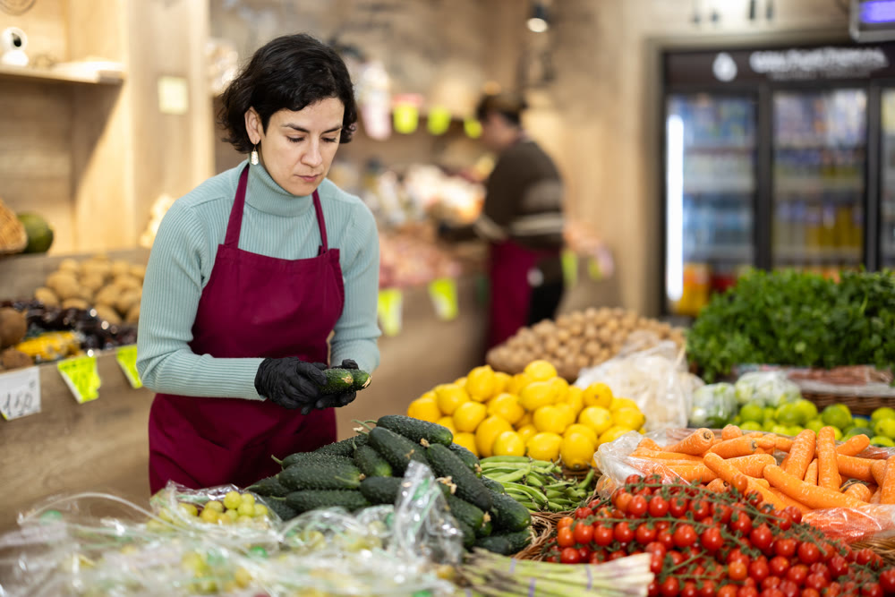 Adult woman seller puts cucumbers on display