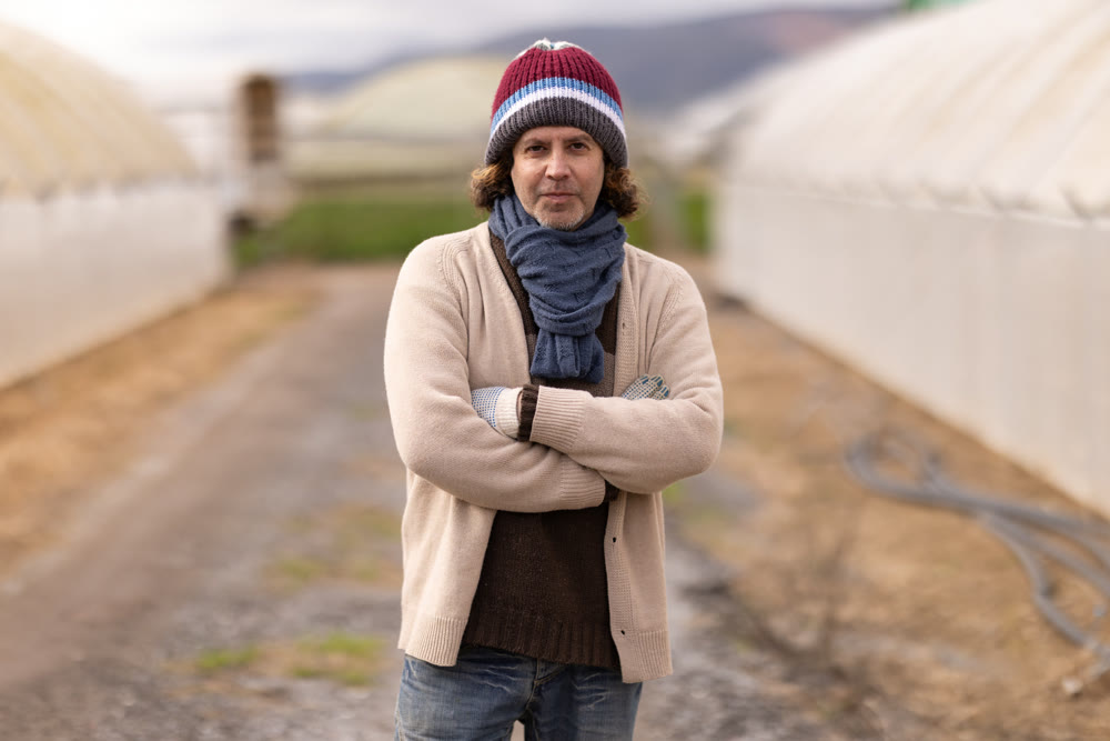 Adult man farmer with greenhouses in background