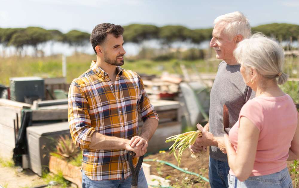 Elderly couple and young man talking together on farm field