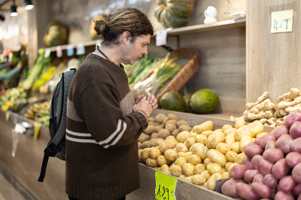 Grocery shopping - male shopper choosing vegetables on supermarket counter