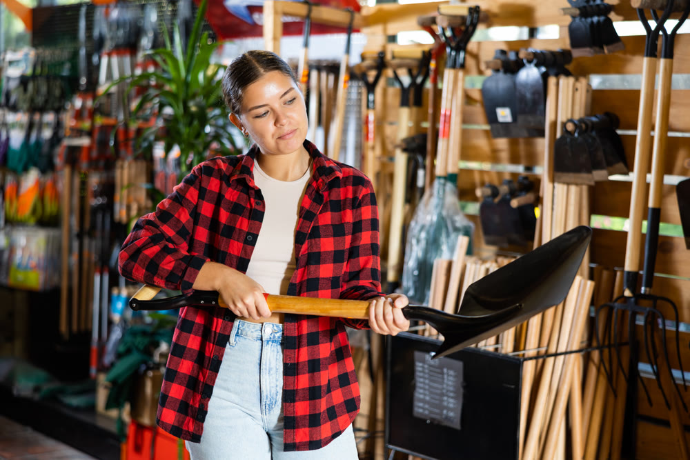 Female farmer choosing shovel in gardening store