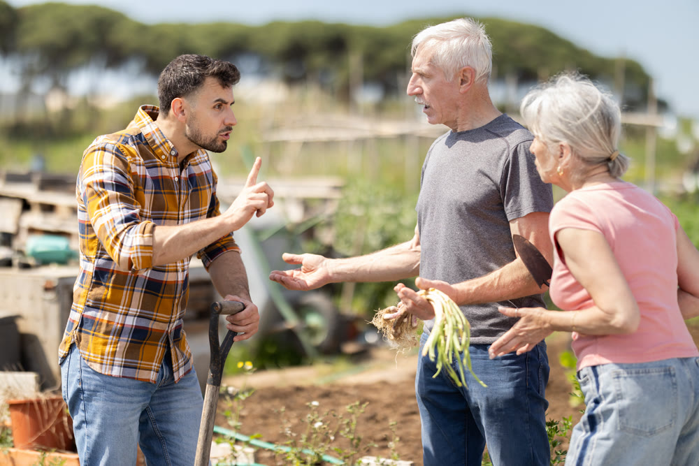 Elderly couple and young man arguing on farm field