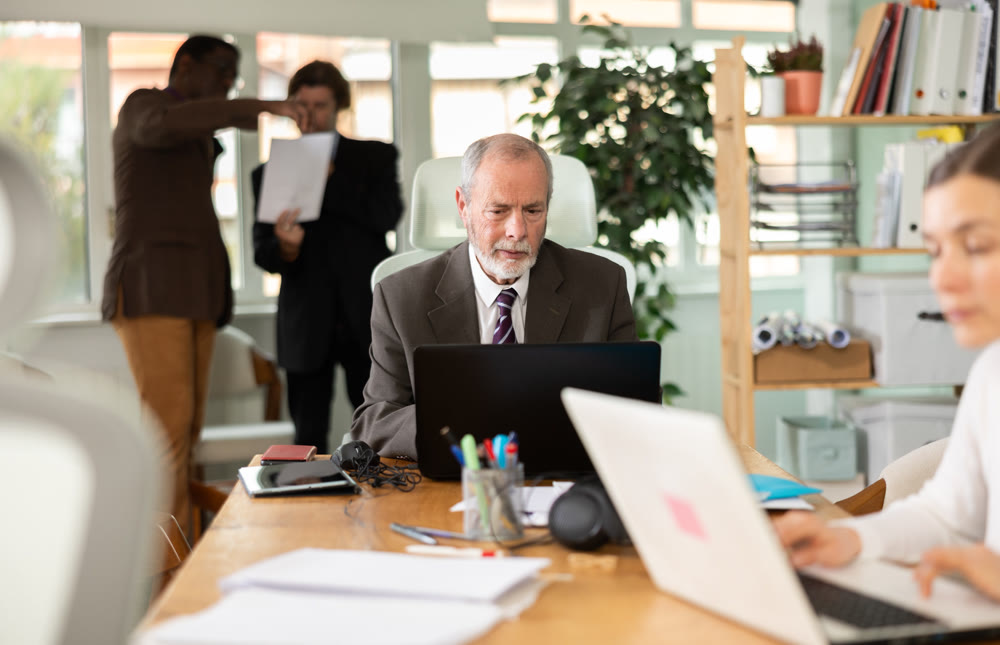 Elderly man working in office with laptop